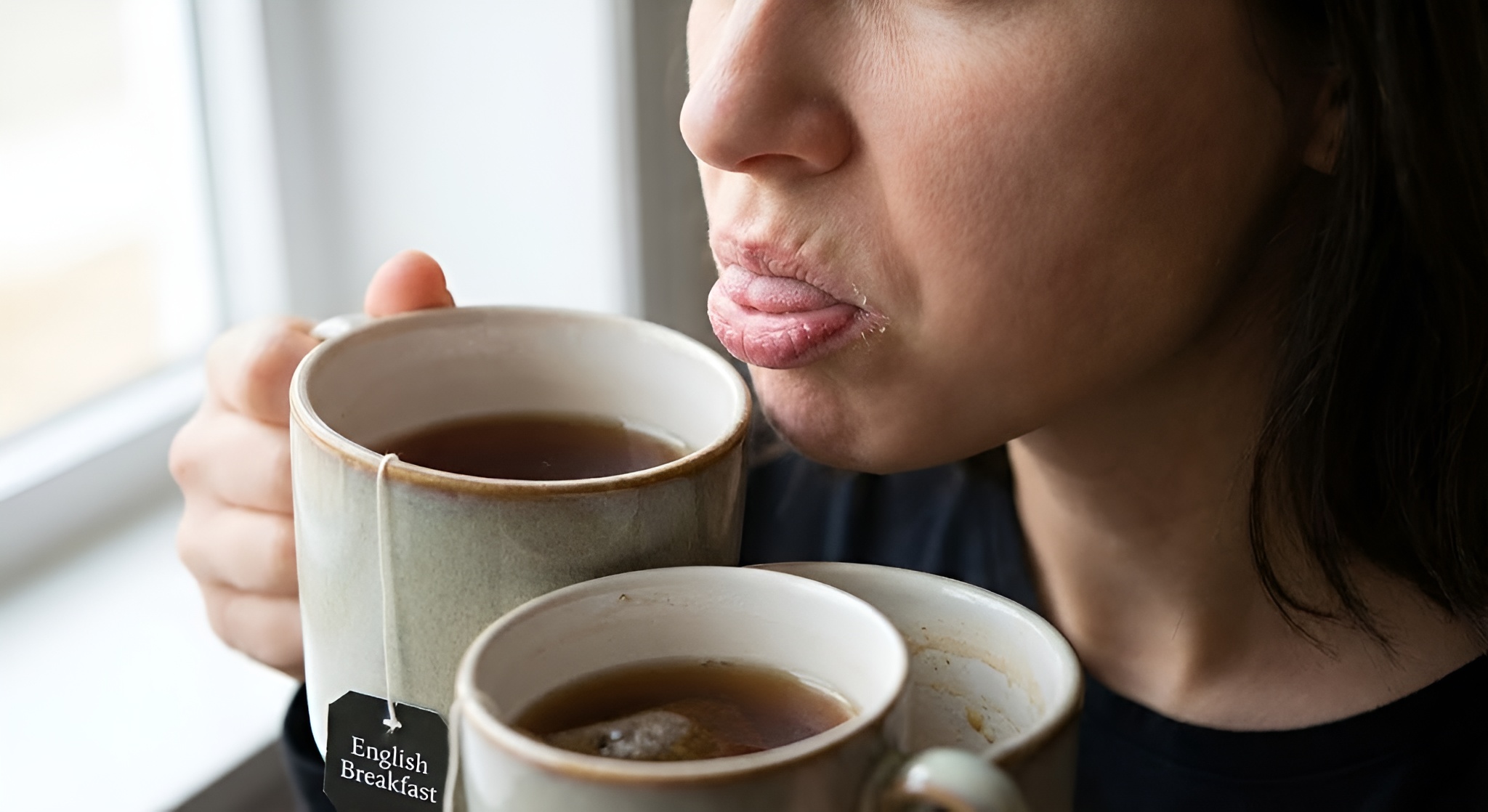 A close-up illustration of a tongue experiencing the dry, puckering sensation of astringency next to a tea leaf.