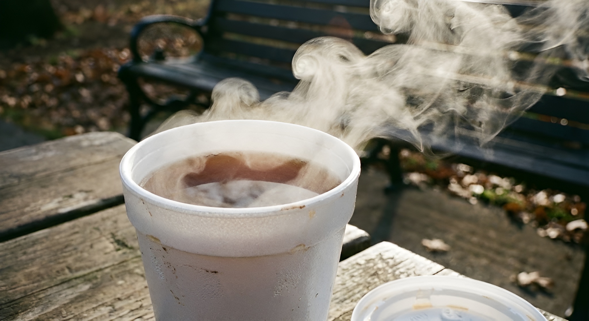 A styrofoam cup containing hot tea with visible steam rising.
